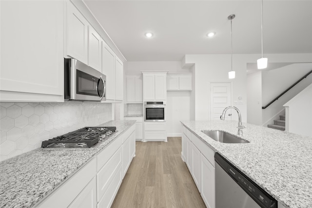 kitchen with white cabinetry, sink, stainless steel appliances, light stone counters, and light hardwood / wood-style floors