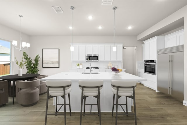 kitchen featuring a center island with sink, a breakfast bar, a sink, stainless steel appliances, and backsplash