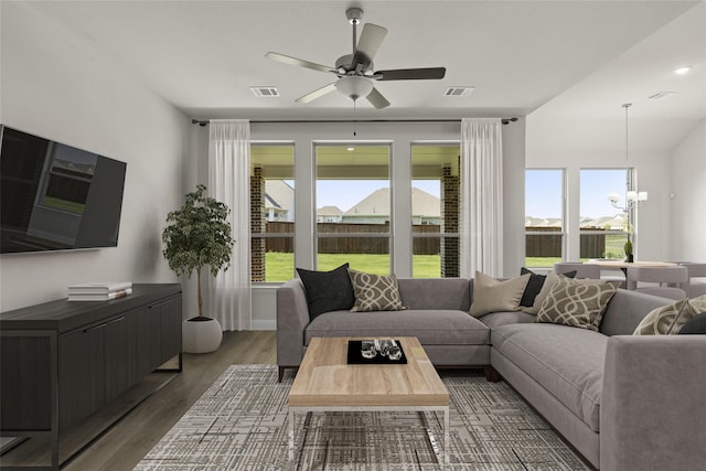 living room with ceiling fan with notable chandelier and dark hardwood / wood-style flooring