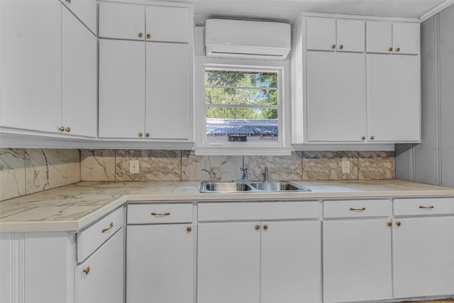 kitchen with tasteful backsplash, an AC wall unit, sink, and white cabinets