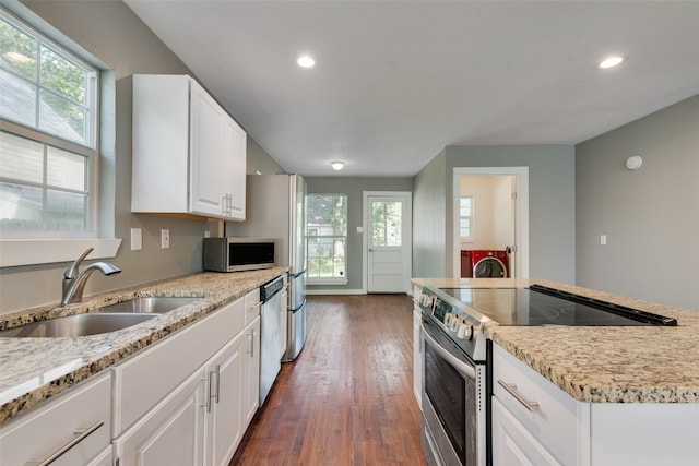 kitchen featuring appliances with stainless steel finishes, dark wood-type flooring, light stone counters, white cabinets, and sink