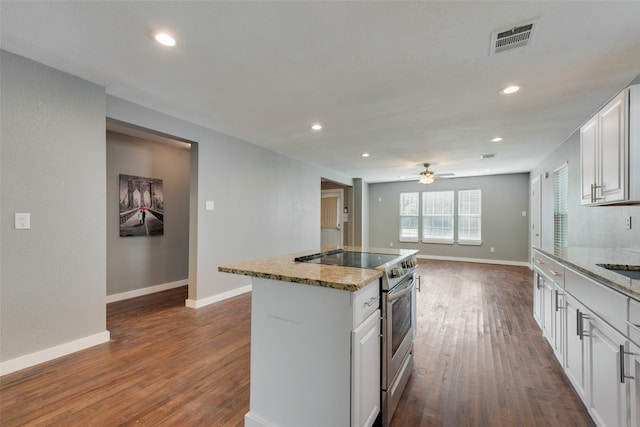 kitchen featuring stainless steel range with electric cooktop, white cabinets, an island with sink, and dark hardwood / wood-style flooring