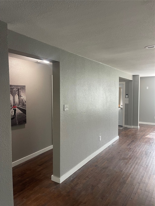 unfurnished room with a textured ceiling and dark hardwood / wood-style floors