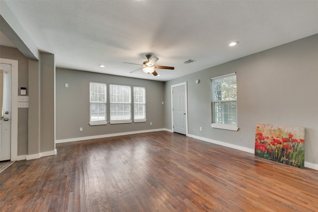 empty room featuring ceiling fan, a textured ceiling, plenty of natural light, and dark hardwood / wood-style floors