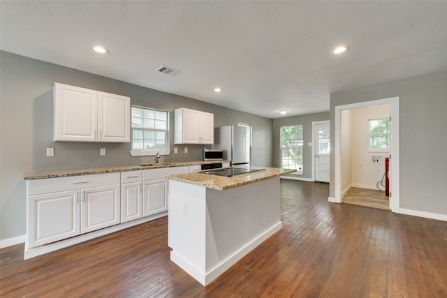 kitchen featuring white cabinets, a wealth of natural light, dark wood-type flooring, and a kitchen island