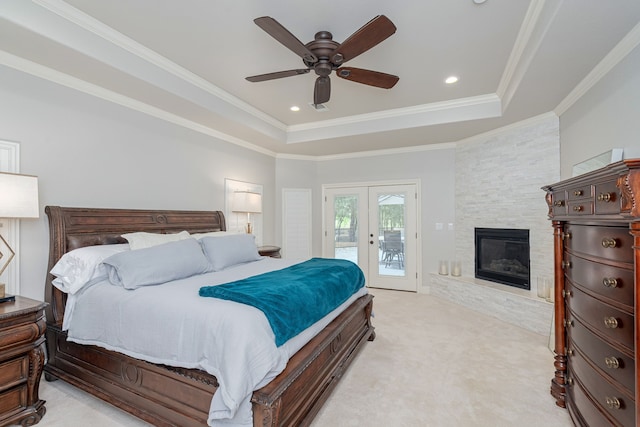 bedroom with ceiling fan, light carpet, access to exterior, and a tray ceiling