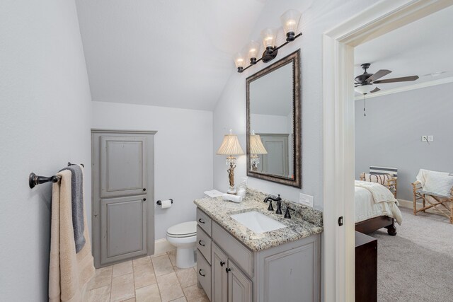 bathroom featuring tile patterned flooring, toilet, vanity, ceiling fan, and vaulted ceiling