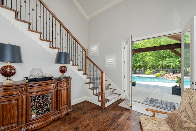 stairs with ornamental molding, high vaulted ceiling, baseboards, and wood finished floors