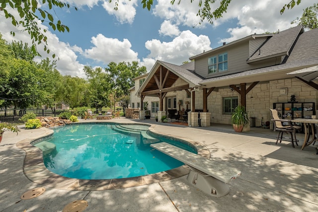 view of pool featuring a diving board, a patio area, fence, and a fenced in pool