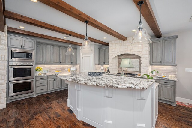 kitchen with decorative light fixtures, dark hardwood / wood-style flooring, beamed ceiling, appliances with stainless steel finishes, and backsplash