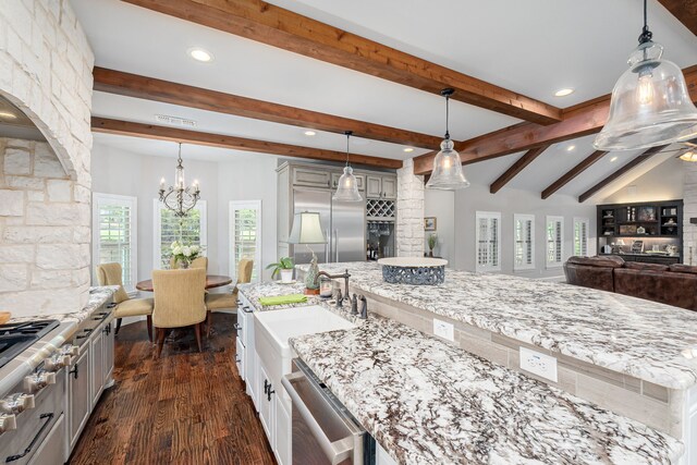 kitchen featuring appliances with stainless steel finishes, dark hardwood / wood-style flooring, decorative light fixtures, and an island with sink