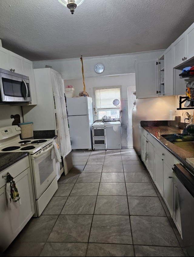 kitchen featuring tile patterned floors, a textured ceiling, white cabinets, and stainless steel appliances