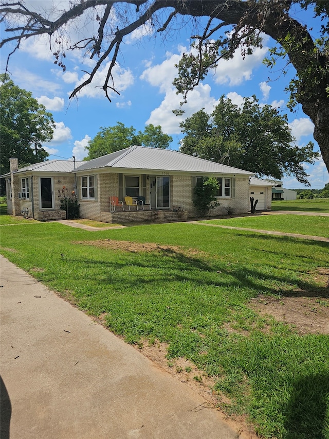 ranch-style home featuring a garage, covered porch, and a front yard