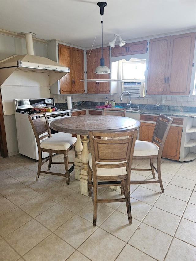 kitchen featuring pendant lighting, stove, light tile patterned floors, and backsplash