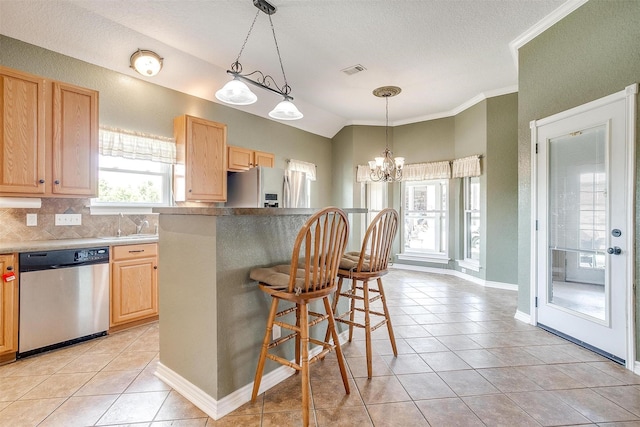 kitchen with lofted ceiling, a breakfast bar area, appliances with stainless steel finishes, an inviting chandelier, and light brown cabinets