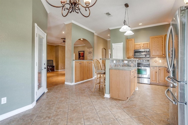 kitchen featuring a breakfast bar area, hanging light fixtures, stainless steel appliances, a center island, and light brown cabinetry