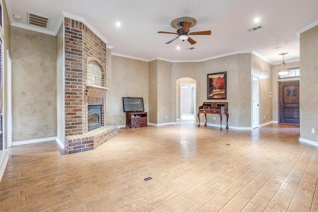 unfurnished living room with crown molding, a brick fireplace, ceiling fan, and light hardwood / wood-style floors