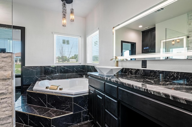 bathroom featuring vanity, a wealth of natural light, and tiled bath