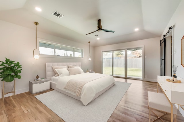 bedroom featuring light wood-type flooring, ceiling fan, access to exterior, and a barn door