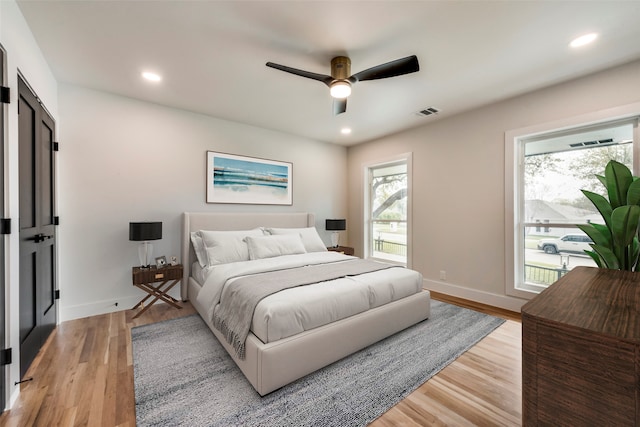 bedroom featuring ceiling fan, light wood-type flooring, and multiple windows