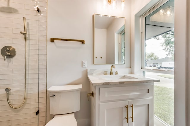 bathroom featuring vanity, toilet, and tiled shower