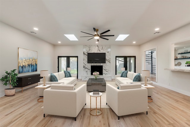 living room featuring a skylight, plenty of natural light, and light hardwood / wood-style flooring