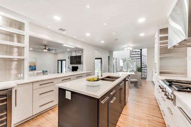 kitchen with white cabinets, appliances with stainless steel finishes, sink, wall chimney range hood, and beverage cooler