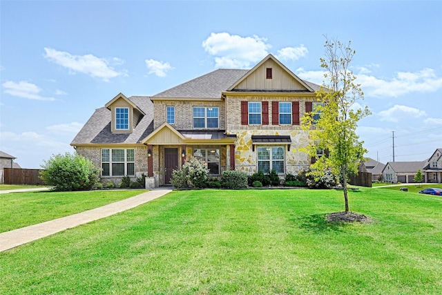 craftsman-style home with fence, a front lawn, board and batten siding, and brick siding