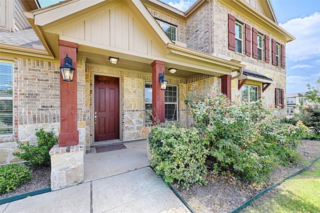 entrance to property with stone siding, a porch, and board and batten siding