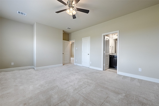 unfurnished bedroom with connected bathroom, light colored carpet, and ceiling fan