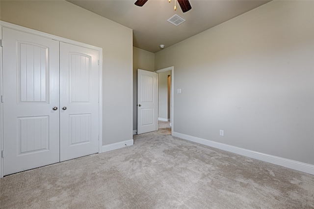 unfurnished bedroom featuring a closet, light colored carpet, and ceiling fan