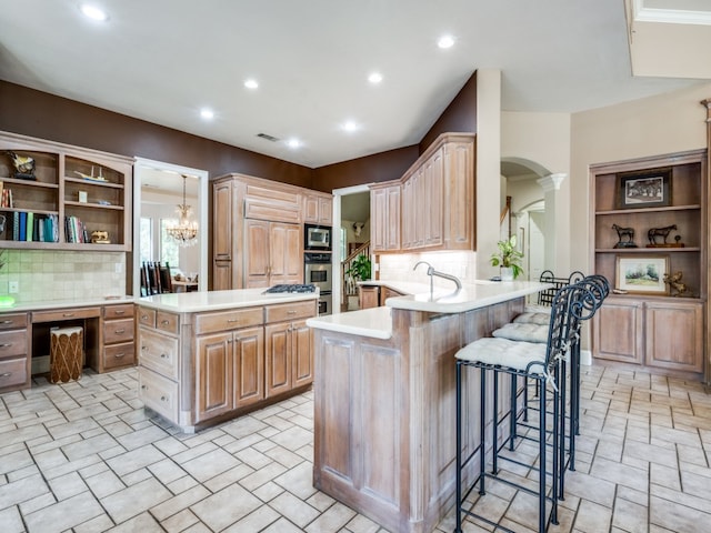 kitchen with a breakfast bar, built in desk, decorative backsplash, kitchen peninsula, and stainless steel appliances