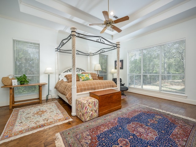 bedroom featuring dark hardwood / wood-style floors, a tray ceiling, ornamental molding, and ceiling fan