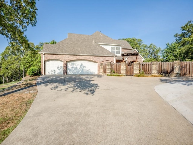 10783 Stagecoach Pass, Pilot Point, TX 76258 - view of front of house featuring a gate, driveway, brick siding, an attached garage, and a shingled roof