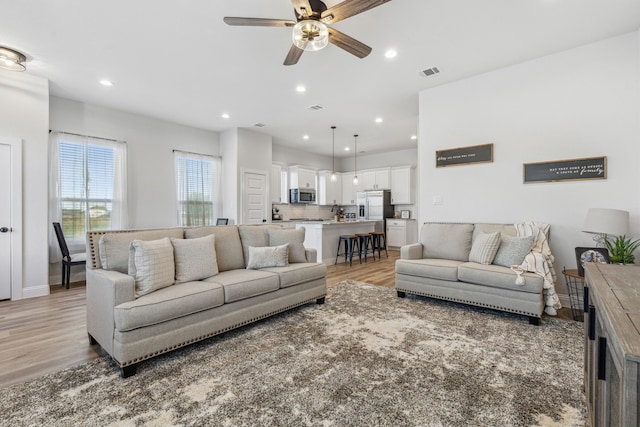 living room featuring ceiling fan and light hardwood / wood-style flooring