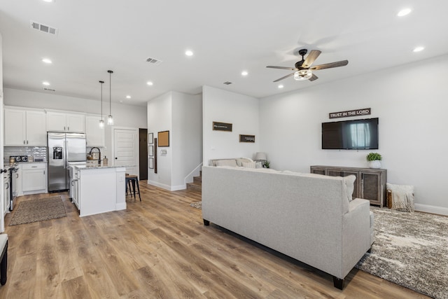 living room featuring ceiling fan and light hardwood / wood-style flooring