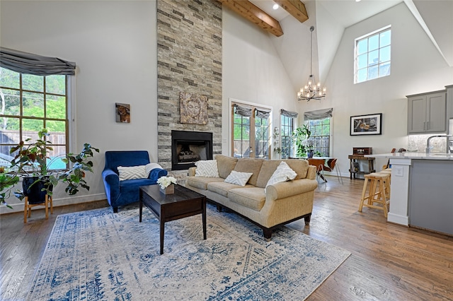 living room with light wood-type flooring, high vaulted ceiling, a wealth of natural light, and a stone fireplace