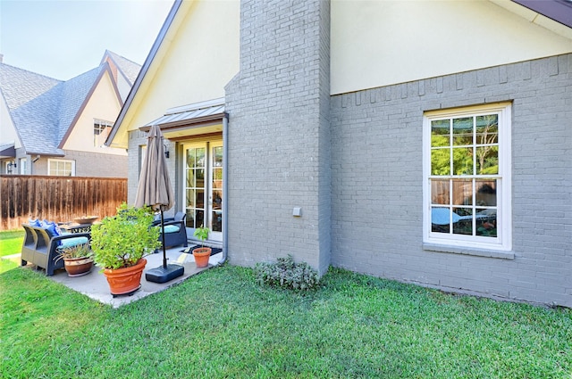 view of home's exterior featuring brick siding, a lawn, a standing seam roof, fence, and metal roof