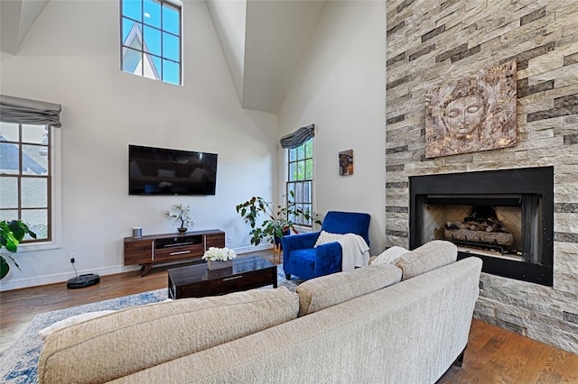 living room with a stone fireplace, high vaulted ceiling, and dark hardwood / wood-style flooring