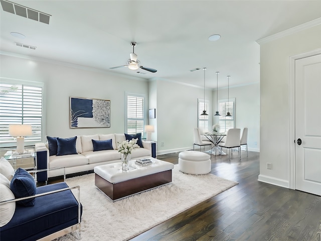 living room featuring a wealth of natural light, dark wood-type flooring, ornamental molding, and ceiling fan