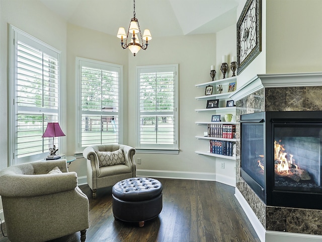 sitting room with dark wood-style floors, a fireplace, baseboards, and a chandelier