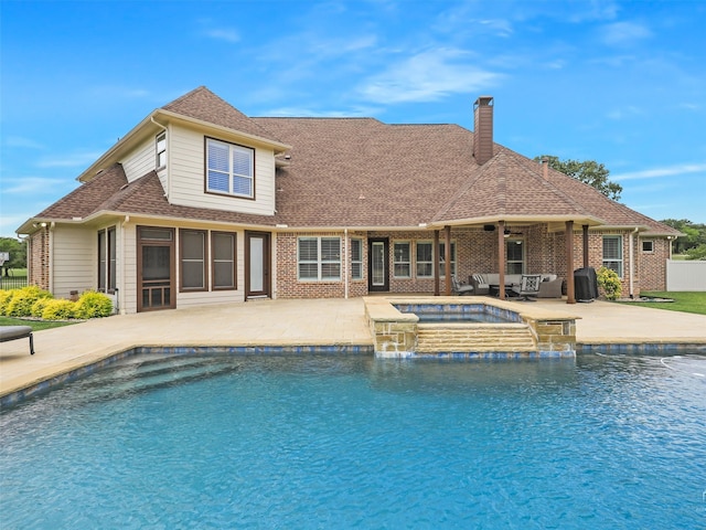 rear view of property featuring a pool with hot tub, a patio area, and pool water feature