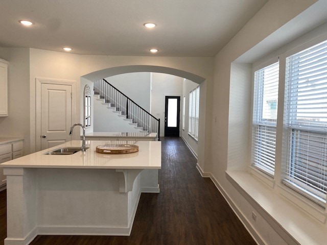 kitchen featuring white cabinetry, a kitchen bar, dark hardwood / wood-style floors, sink, and a center island with sink