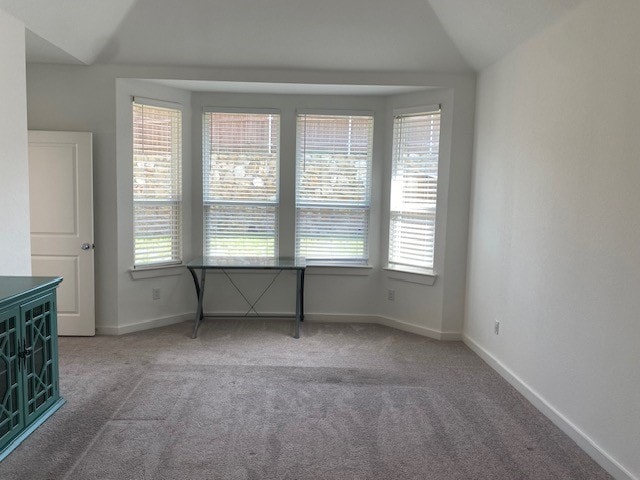 empty room featuring a wealth of natural light, light colored carpet, and vaulted ceiling