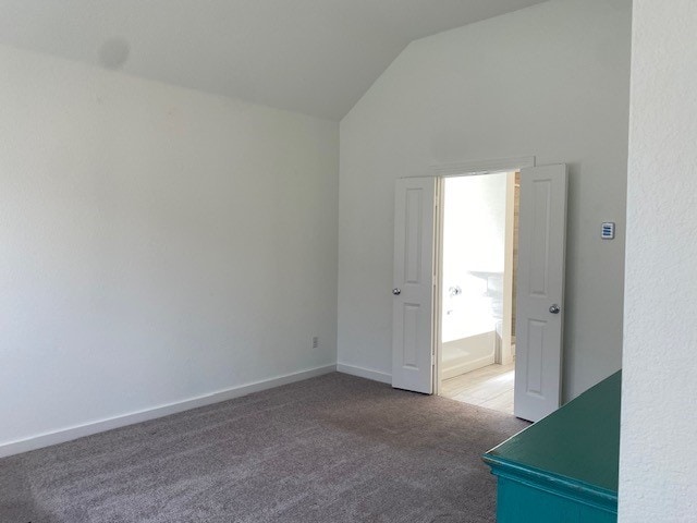 unfurnished bedroom with high vaulted ceiling and carpet