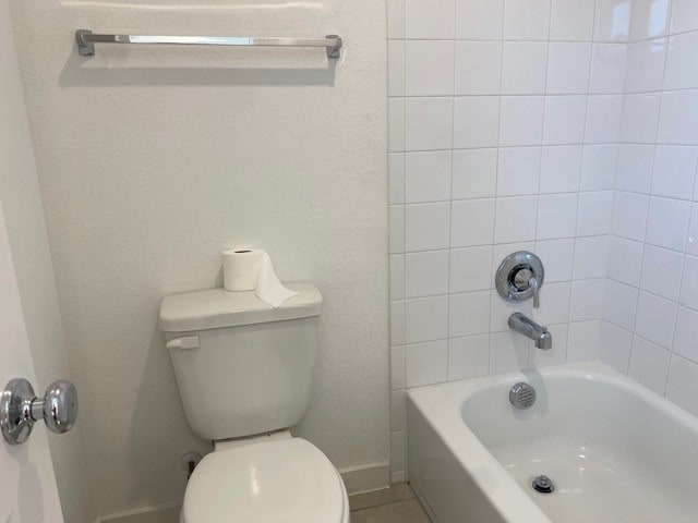 bathroom with tiled shower / bath combo and toilet