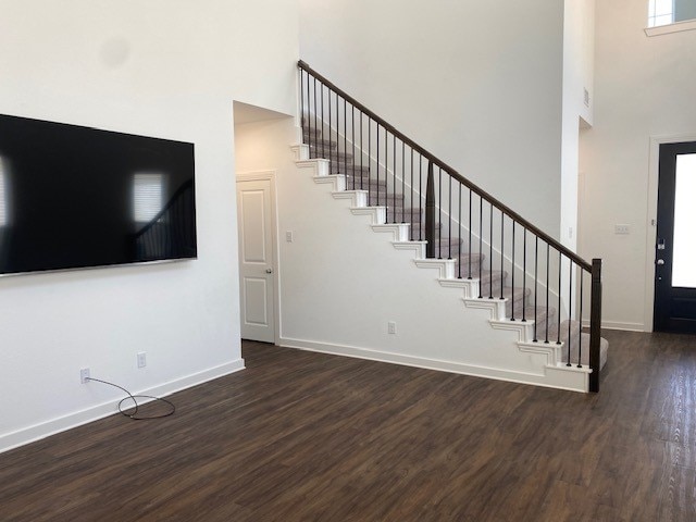 unfurnished living room with a high ceiling and dark wood-type flooring