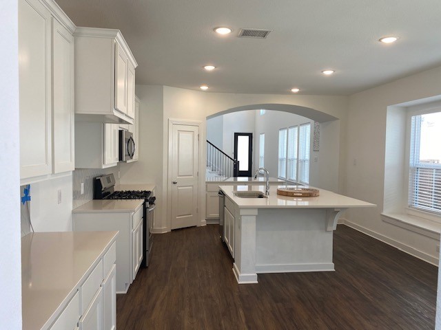 kitchen with white cabinetry, a center island with sink, dark hardwood / wood-style flooring, stainless steel appliances, and sink