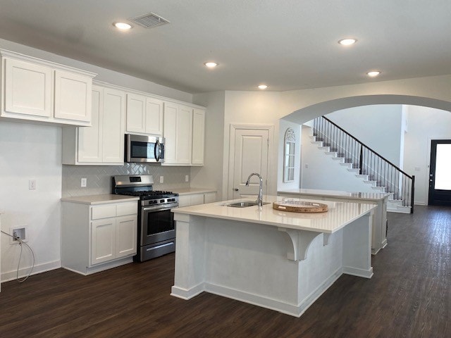 kitchen with a center island with sink, stainless steel appliances, dark hardwood / wood-style flooring, and sink