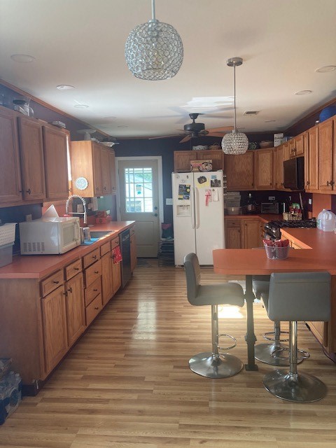 kitchen with black appliances, sink, pendant lighting, light wood-type flooring, and ceiling fan